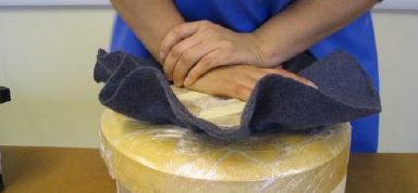 Making men's hats pushing the blocked crown through the brim block.