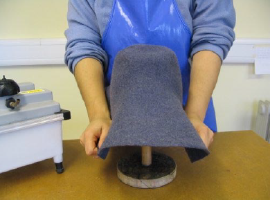 Making men's hats, stretching the felt over the crown block.